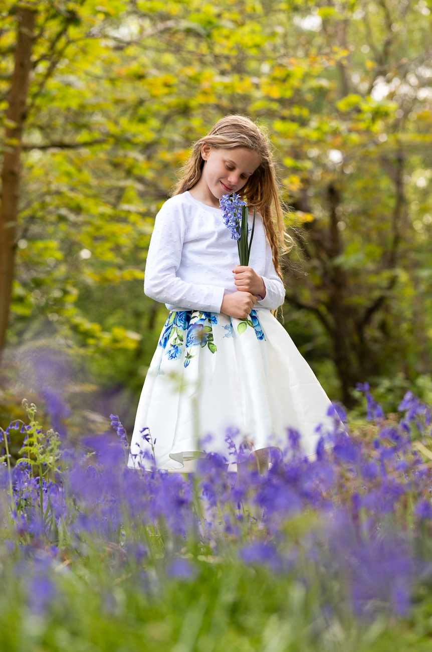 Girl holding a bluebell flower in the woods