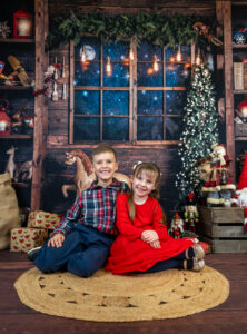 Boy and girl sitting down on a Christmas scene