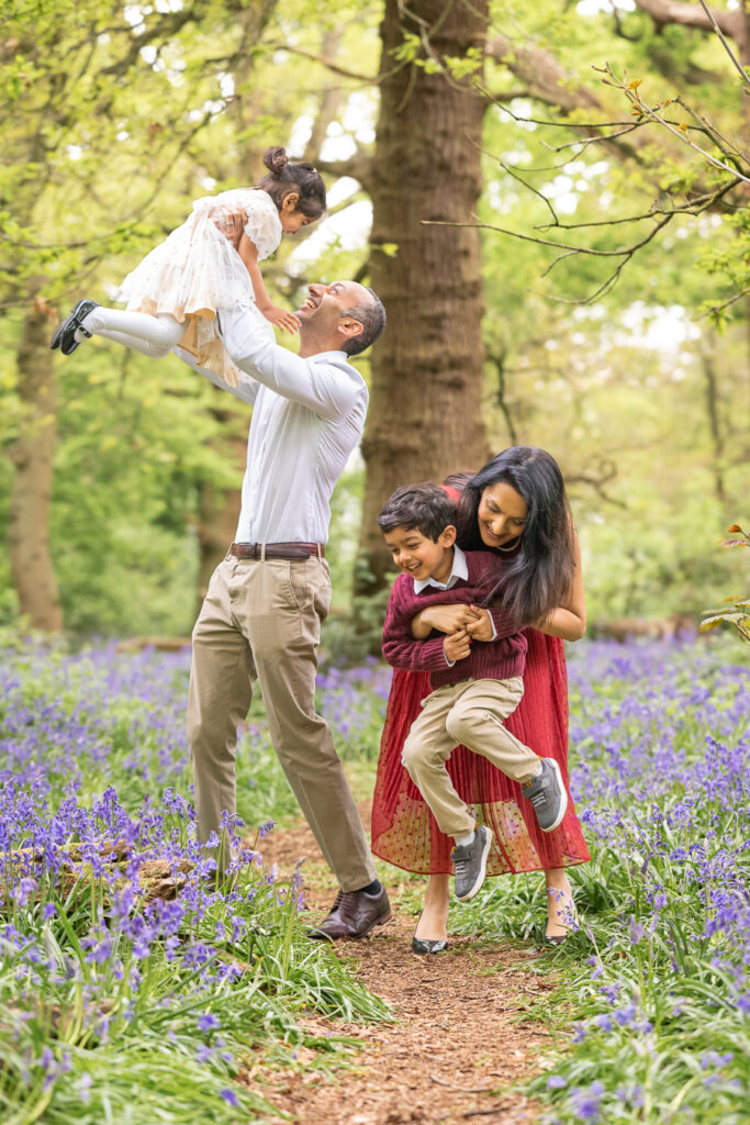 Family playing with their children in the bluebell woods