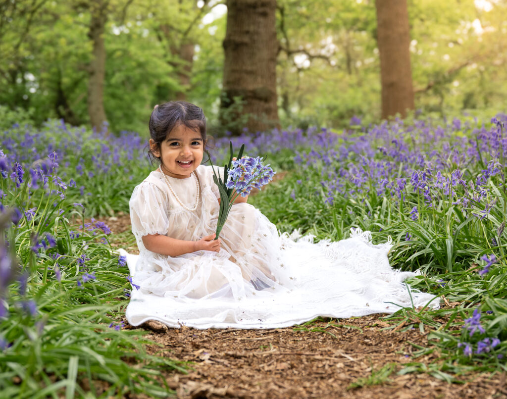 Girl sitting holding bluebells in the woods