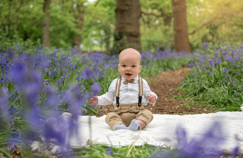 Baby boy witting in the bluebell woods
