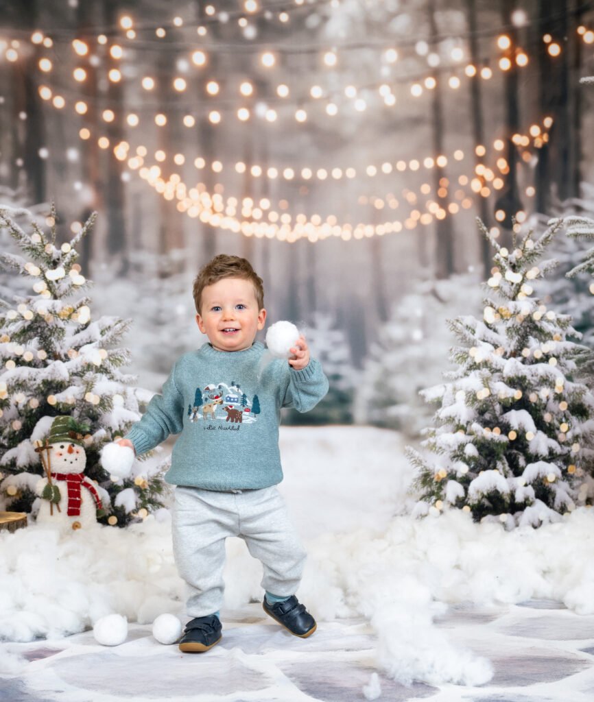 Boy looking cheeky holding snowballs having his photo taken