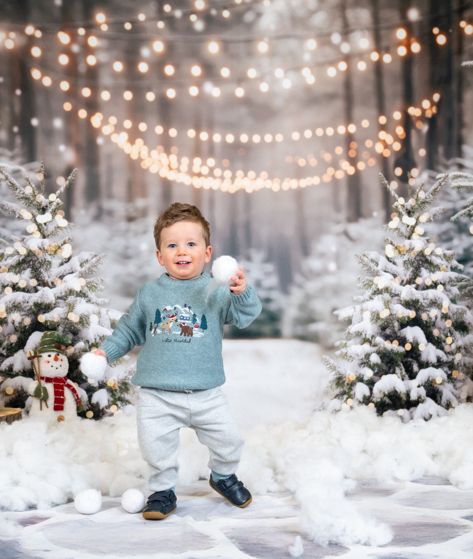 Boy looking cheeky holding snowballs having his photo taken