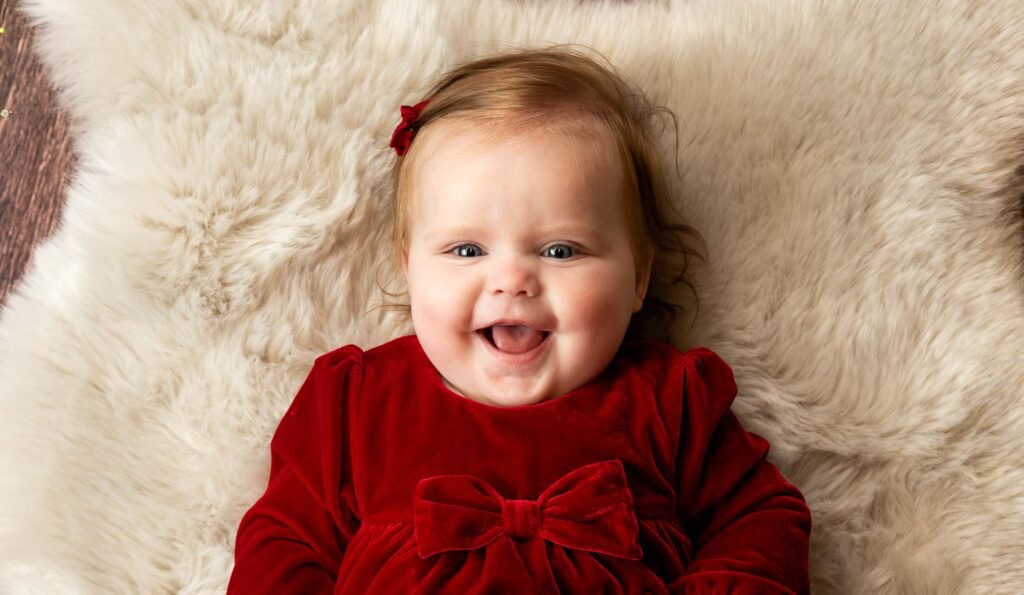 Toddler in a red dress on a cosy rug during an at home Christmas photoshoot in Ware