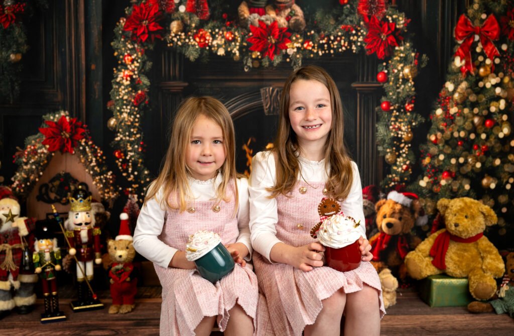 Two girls with hot chocolates by the fireplace smiling