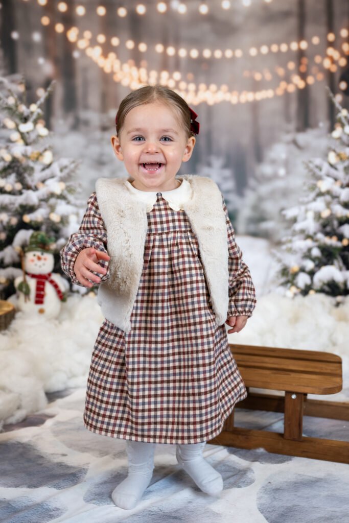 Girl standing, smiling and laughing next to a sled