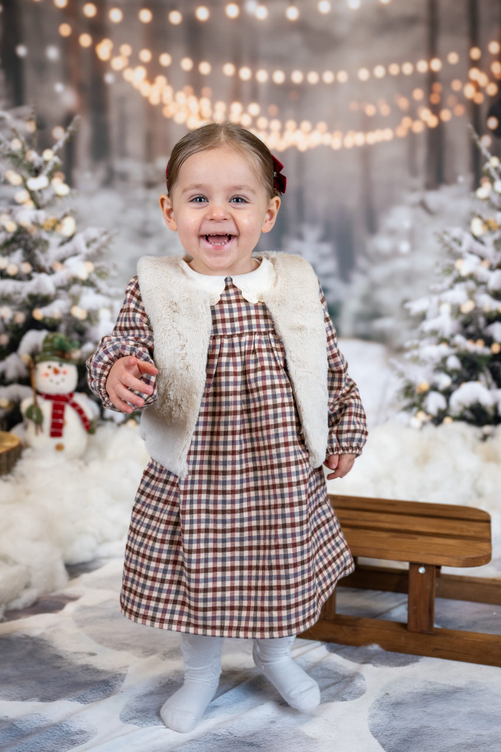 Girl standing, smiling and laughing next to a sled