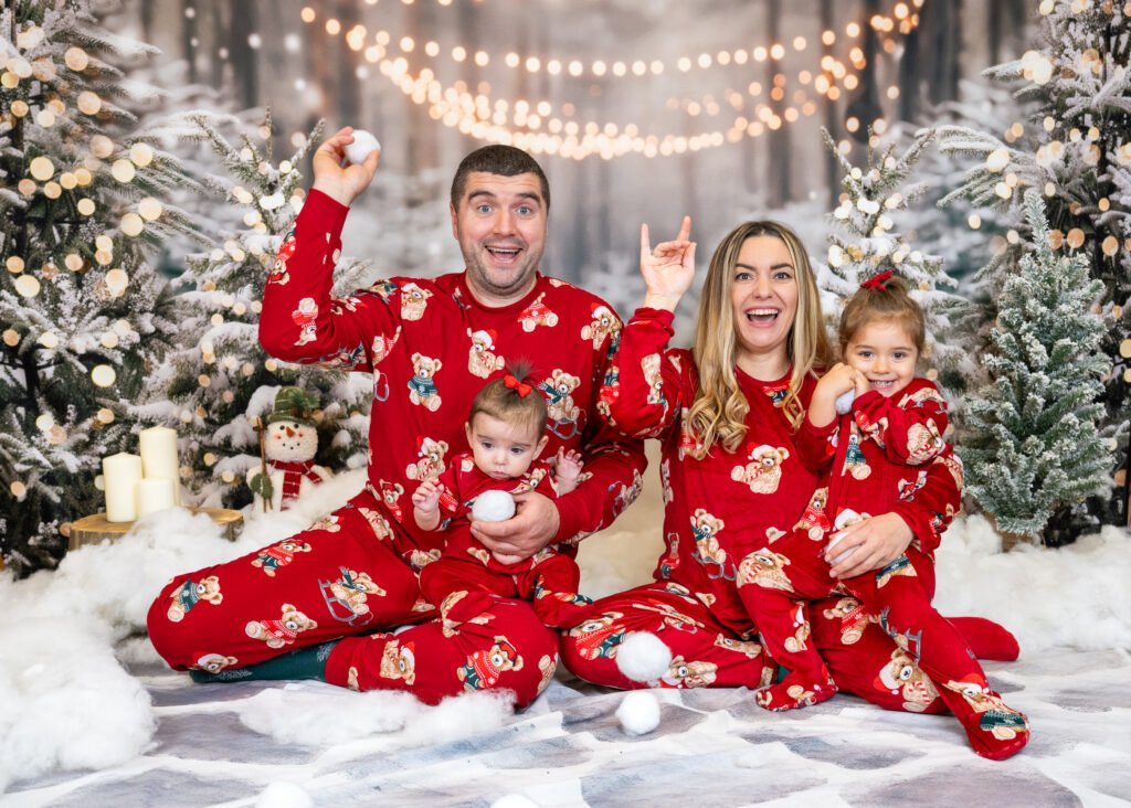 Family in PJs in the snow smiling and playing during a photoshoot